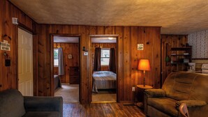 Una camera accogliente in stile baita, con un letto, una poltrona, una lampada e un divano.