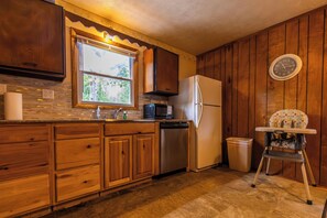 A kitchen with wooden cabinets, a stainless steel dishwasher, a refrigerator, and a microwave. - Peaceful Cabin on Kentucky Lake (Benton)