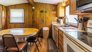 Una cocina funcional con paredes de madera, una mesa redonda y lo esencial.