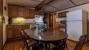 A compact kitchen with wooden cabinets, a dining table with chairs, a coffee maker, and a microwave. - Spacious Cabin on Kentucky Lake (Benton)