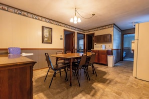A dining area with a wooden table and chairs, a kitchen with cabinets and appliances, and a hallway leading to another room. - Spacious Cabin overlooking Kentucky Lake (Benton)