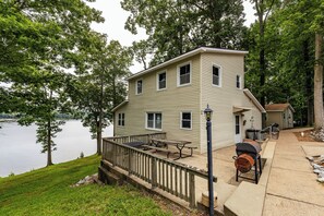 Une maison à deux étages avec une terrasse, un barbecue et une vue sur un lac.