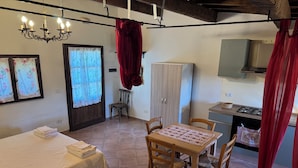 Une pièce confortable comprenant un lit, une table avec des chaises, une armoire et un coin cuisine.