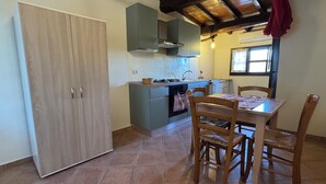 Une cuisine avec une table et des chaises en bois, une cuisinière et un évier.