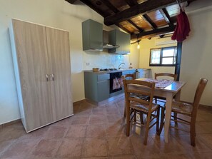 Una cocina con una mesa y sillas de madera, una estufa y un lavamanos.