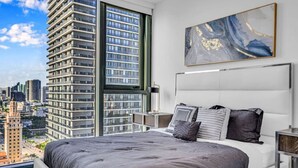 Une chambre moderne avec un grand lit, une vue sur la ville et un tableau accroché au mur.