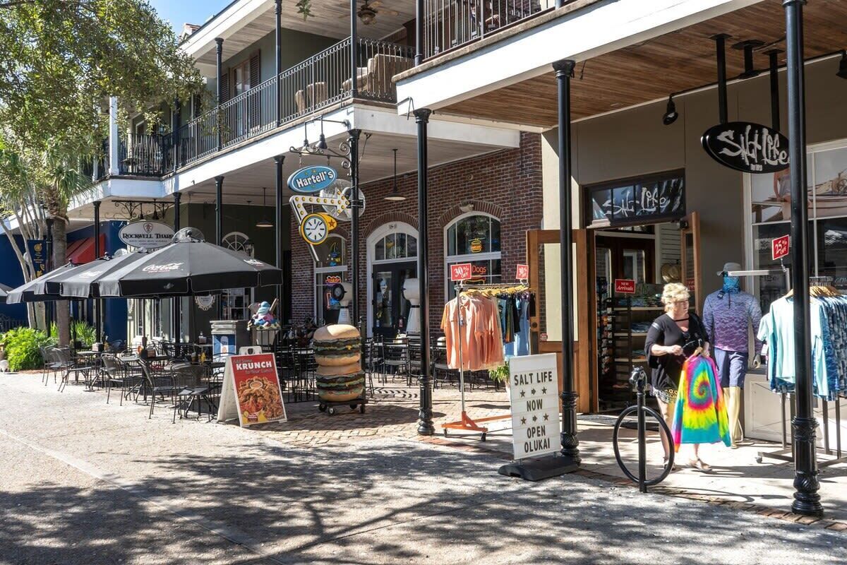 Una calle con mesas al aire libre, un letrero que dice 'Salt Life' y una tienda de ropa.