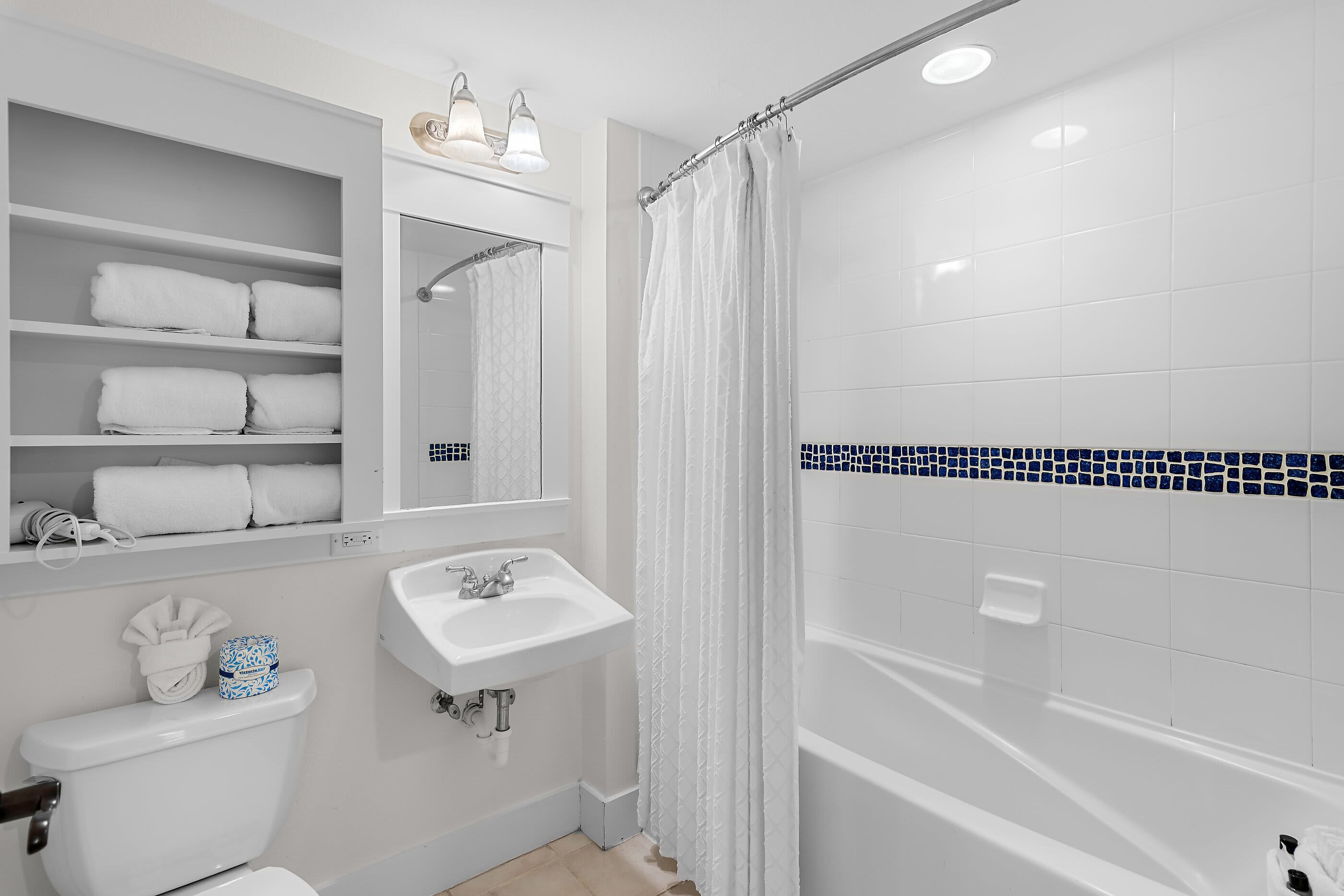 Un baño con inodoro, lavamanos y zona de ducha.