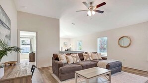 Ein geräumiges Wohnzimmer mit einer großen Eckcouch, einem Couchtisch und einem Essbereich mit Holztisch und Stühlen.