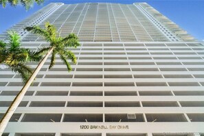 A high-rise building with a grid-like facade and a palm tree in the foreground. - Luxurious private unit with parking (Miami)