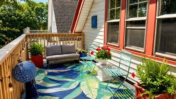 A covered patio with a sofa, chairs, and potted plants.