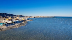 Une ville côtière avec des bâtiments qui bordent le littoral, un ciel bleu dégagé et une mer calme.