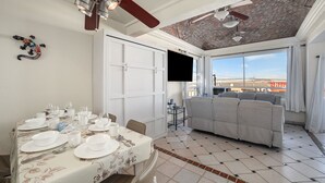 Un coin repas avec une table dressée pour quatre personnes, un canapé et un téléviseur fixé au mur.