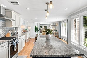 A modern kitchen with granite countertops, a central island, and a view to the dining area. - Elegant retreat, 10 min. from Newport; game room, fire pit, & huge deck! (Jamestown)