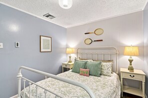 A bedroom with a bed, two bedside tables, a wall-mounted lamp, a ceiling vent, and a framed picture. - Elegant retreat, 10 min. from Newport; game room, fire pit, & huge deck! (Jamestown)