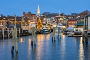 A waterfront town with a prominent church steeple, docked boats, and a Christmas tree decorated with lights. - Elegant retreat, 10 min. from Newport; game room, fire pit, & huge deck! (Jamestown)