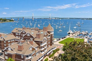 A marina with numerous boats, a prominent bridge in the background, and residential buildings with balconies. - Elegant retreat, 10 min. from Newport; game room, fire pit, & huge deck! (Jamestown)