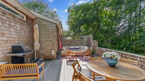 Eine Holzterrasse mit Grill, Sitzgelegenheit und einem Blumentopf.