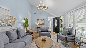 Ein geräumiges Wohnzimmer mit grauem Sofa, einem Holztisch und einem grauen Sessel.