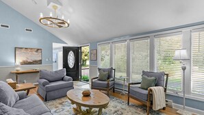 Ein Wohnzimmer mit einer Couch, Sesseln, einem Couchtisch und einem Kronleuchter.