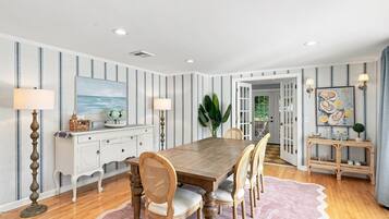 A dining area with a wooden table and chairs, a white cabinet, and striped wallpaper.