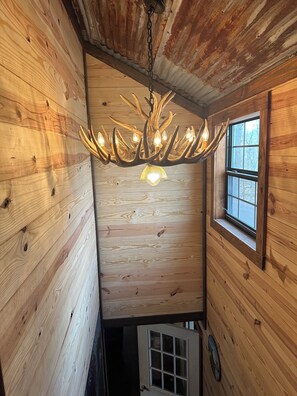 A wooden interior with a chandelier, a window, and a door.