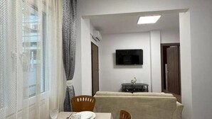 A dining area with a table set for two, a sofa, and a TV in the background. - Le Grace Urban Retreat Near Near Citycenter Sea (Kalamaria)