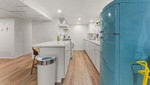 A modern kitchen with a blue refrigerator, white cabinets, and a wooden floor. - Welcoming Home near Downtown Boise (Boise)