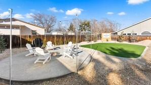 A backyard with a concrete patio, outdoor seating, a barbecue grill, and a sign for the Denton Lodge. - Welcoming Home near Downtown Boise (Boise)