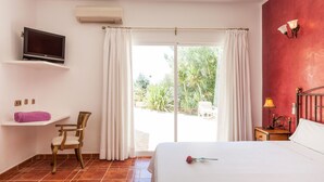 A bedroom with a bed, a TV, a chair, a desk, and a view of the outdoors. - Teresa Fontalba_Ses Casetes (Sant Jordi de Ses Sali)