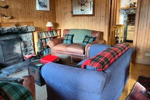 A cozy living room with a fireplace, a sofa, a bookshelf, and a dining area.