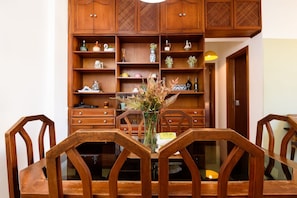 Ein Essbereich mit einem Holztisch, Stühlen und einer Schrank mit Regalen.