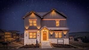 A two-story house with a stone facade, a wooden front porch, and a clear night sky.
