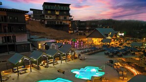 A resort with multiple buildings, outdoor seating areas, and a pool.