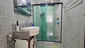 Baño con lavamanos, espejo y zona de ducha.