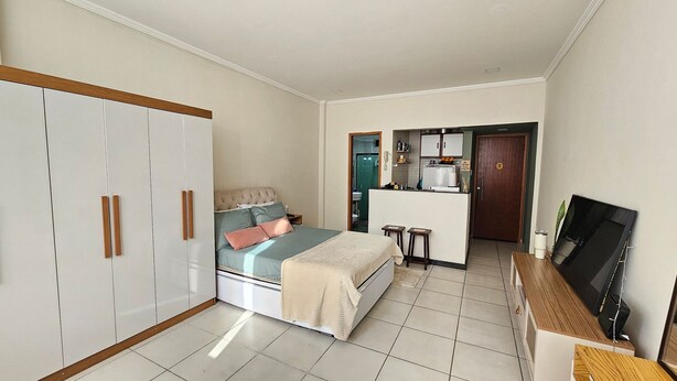 Un dormitorio con cama, armario y una pequeña kitchenette.
