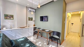 Eine moderne Küche mit Essbereich, ausgestattet mit einer Couch, einem Tisch mit Stühlen und einem an der Wand befestigten Fernseher.