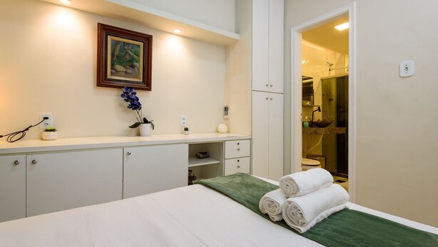 Ein Hotelzimmer mit Bett, Schreibtisch, Spiegel, einem gerahmten Bild und einem durchgegangene Tür sichtbaren Badezimmer.