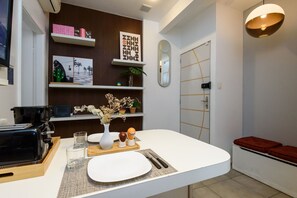 Cozinha moderna com cafeteira, bancada branca e área de refeições com banco.