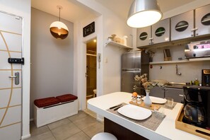 Cozinha moderna com forno embutido, máquina de café e área de refeições com banco e um vaso.