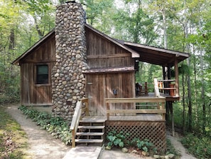 A rustic cabin with a stone chimney, wooden deck, and a small porch. - Old Man's Haven - Cabin 3 (Logan)