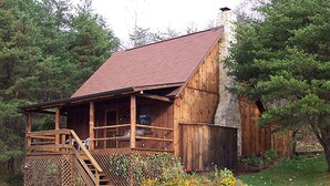 Eine rustikale Holzhütte mit Veranda, Schornstein und Holzzaun.