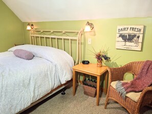 Un dormitorio con cama, una mesita de noche con reloj, una silla de mimbre y un letrero en la pared que dice "DAIRY FRESH".