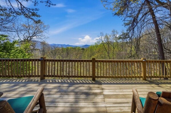 A wooden deck with a railing, overlooking a forested area with mountains in the distance. - Mountain View Log Cabin w Hot Tub & Foosball (Bryson City)
