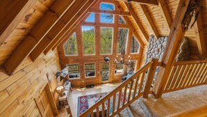 Una baita di legno con una scala, ampie finestre e un muro in pietra.