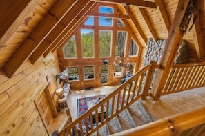 A wooden cabin with a staircase, large windows, and a stone wall. - Mountain View Log Cabin w Hot Tub & Foosball (Bryson City)
