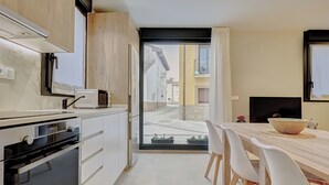 A modern kitchen with a built-in oven, a microwave, and a dining area with a table and chairs. - LA FRAGUA ANCÍN APARTMENT (Ancín)