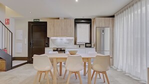 A modern kitchen with a dining area, featuring a large island, white chairs, and a stainless steel refrigerator. - LA FRAGUA ANCÍN APARTMENT (Ancín)
