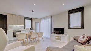 A modern living room with a sofa, TV, and dining area. - LA FRAGUA ANCÍN APARTMENT (Ancín)