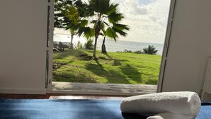 A room with a large window, a blue exercise mat, and a rolled white towel.